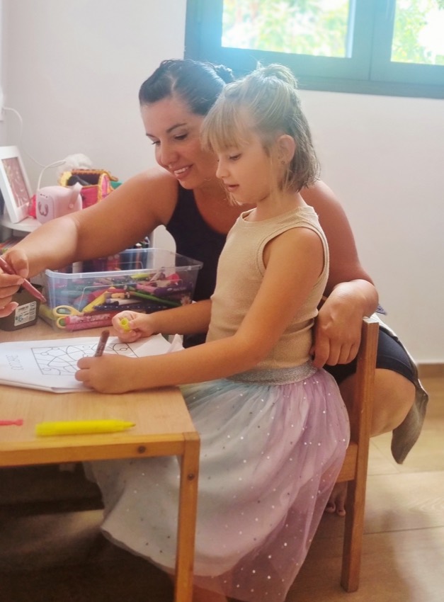 Caroline accompagne une enfant pendant un atelier créatif